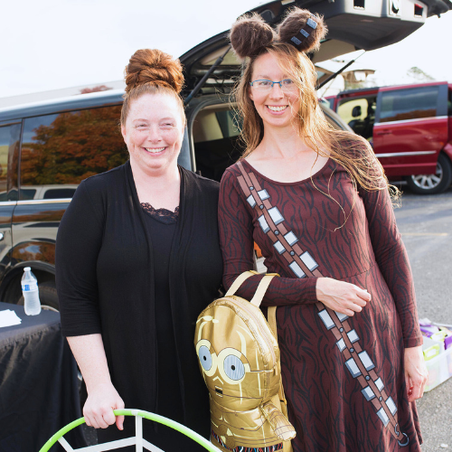 Two people in costume standing in front of vehicle.